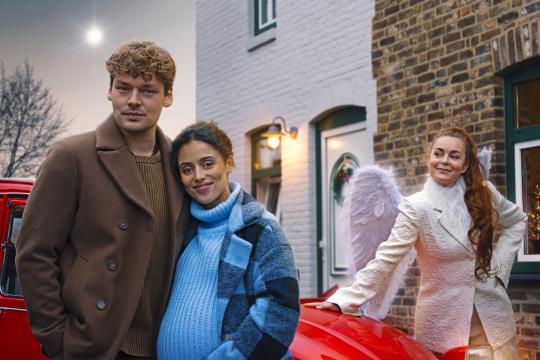 twee personen en een engel voor een rode auto