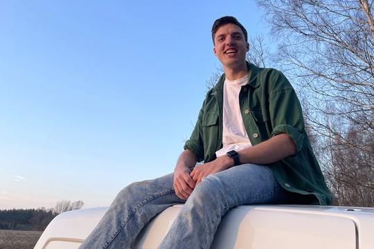 Onderweg naar liefde - Joris 23 Lachende man zit bovenop een camper