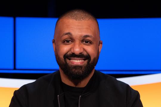 Lachende man met zwarte baard en zwart vest