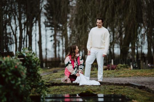 Man in witte kleding en vrouw bij graf