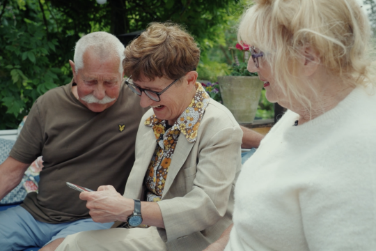 Drie personen op een bankje in de tuin