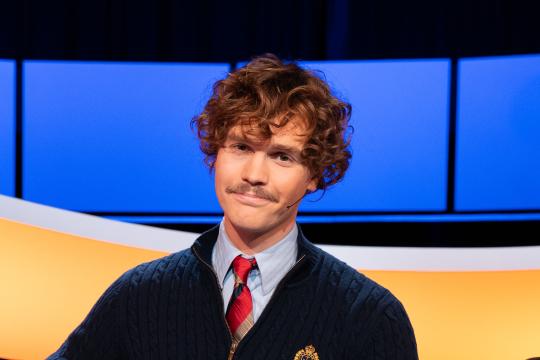 Man met krullen en blauw vest met stropdas