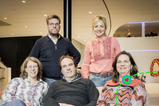 Drie mensen zitten op een bank en twee mensen staan erachter