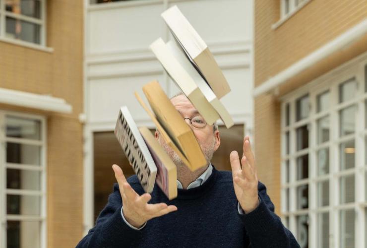 Man gooit een stapel met boeken de lucht in