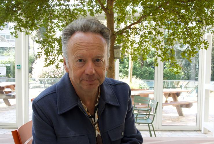 Man met grijs haar op een stoel onder een boom