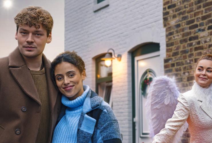 twee personen en een engel voor een rode auto