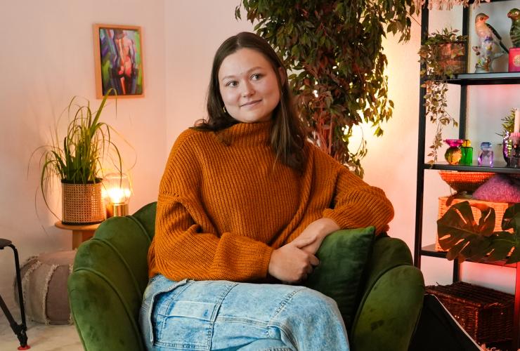 Vrouw poseert in stoel en kijkt naast de camera