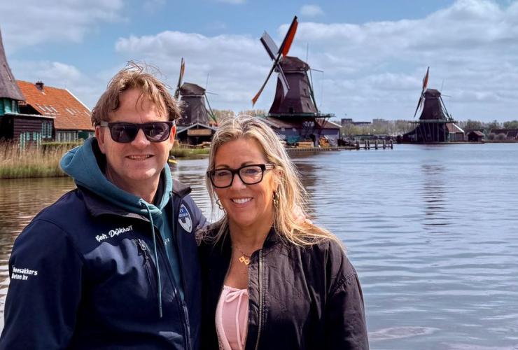 Man en vrouw staan naast elkaar voor Hollandse molens