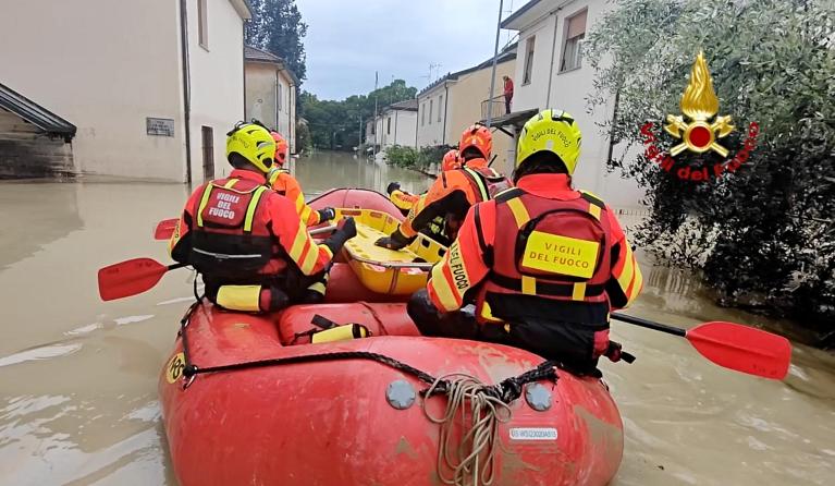This photo taken and issued as a handout on May 17, 2023, by the Vigili del Fuoco, the Italian Corps of Firefighters, shows firefighters on a dinghy looking for potential people in distress in a flooded street in Faenza, Emilia-Romagna region. Heavy rains have caused major floodings in central Italy, where trains were stopped and schools were closed in many towns while people were asked to leave the ground floors of their homes and to avoid going out. The death toll rose to five on May 17, the Forli-Cesena 
