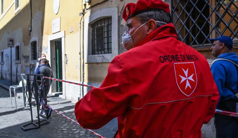 Volunteers from the association Circolo San Pietro economic cuisine, and volunteers of the S.O.d.M (Sovereign Order of Malta) distribute meals to the homeless and people in need, in Via della Lungaretta in the district of Trastevere in Rome on March 20, 2020 during the country's lockdown aimed at stopping the spread of the COVID-19 (new coronavirus) pandemic.