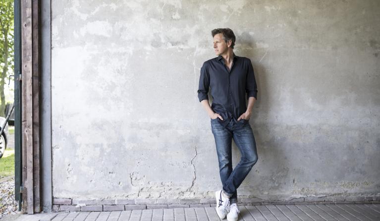 Tom Kleijn staand tegen een grijze muur