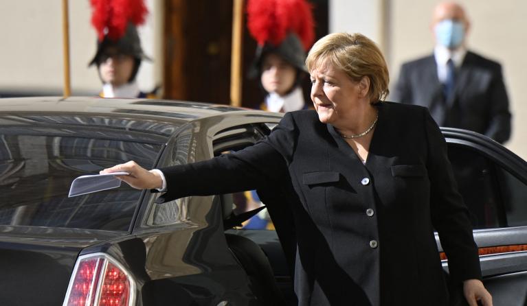 German chancellor Angela Merkel puts a document on her car's trunk as she arrives at the Vatican for a meeting with the Pope on October 7, 2021.