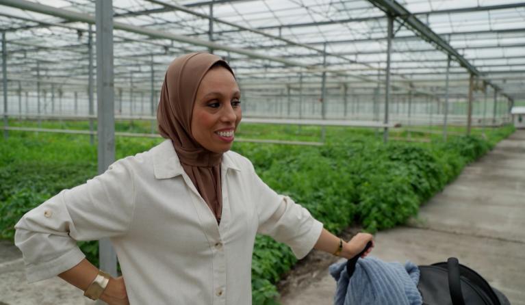 Vrouw met kinderwagen in groene kas