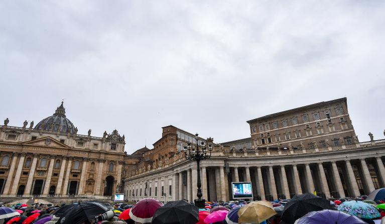 People protect themselves from the rain with an umbrella, as Pope Francis (Top R) speaks from the window of the Apostolic palace overlooking St. Peter's Square during the weekly Angelus prayer in The Vatican on September 27, 2020. Tiziana FABI / AFP