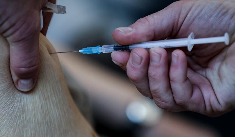 A resident of the Christalain nursing home in Brussels receives a dose of Pfizer-BioNTech Covid-19 vaccine on January 14, 2021 dispensed with a syringe and a needle that allow one extra dose of vaccine per vial. EU's medicines watchdog said on January 8, 2021 that six doses instead of five of the Pfizer-BioNTech coronavirus jab can be extracted from each vial if the correct needles are used, increasing the number of people who can be vaccinated with available supplies.