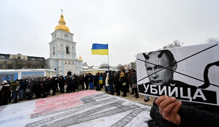 A demonstrator holds a placard depicting Russian president Vladimir Putin signed "Killer" during an action dubbed #SayNOtoPutin in Kyiv on January 9, 2022. 