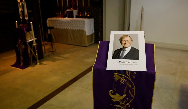 A photograph of Conservative British lawmaker David Amess, who was fatally stabbed, is pictured prior to a service at Saint Peter's Catholic Parish of Eastwood in Leigh-on-Sea in southeast England on October 15, 2021. Conservative British lawmaker David Amess was killed on Friday after being stabbed "multiple times" during an event in his local constituency in southeast England, in the second death of a UK politician while meeting voters since 2016. Local police did not name Amess but said a man had been ar
