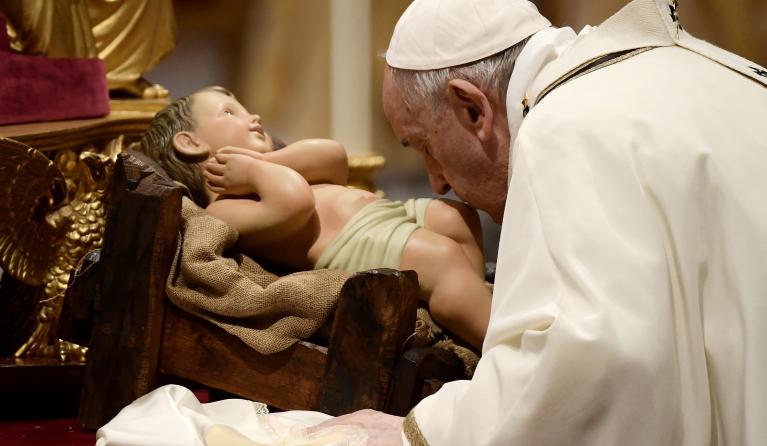 Pope Francis kisses a figurine of baby Jesus during the Christmas Eve mass at St Peter's Basilica in the Vatican, on December 24, 2021. 