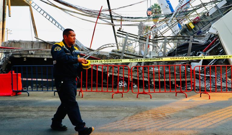 A policeman cordons off the place where the subway car collapsed on the night of 03 May, in Mexico City, Mexico, 05 May 2021. Operators and experts from the Government of Mexico City intensified on 05 May the work to lift the rubble of the bridge of line 12 of the subway that collapsed on 03 May and in which at least 25 people died, as a majority of Mexicans believe that the tragedy was due to serious negligence. EPA/Carlos Ramirez