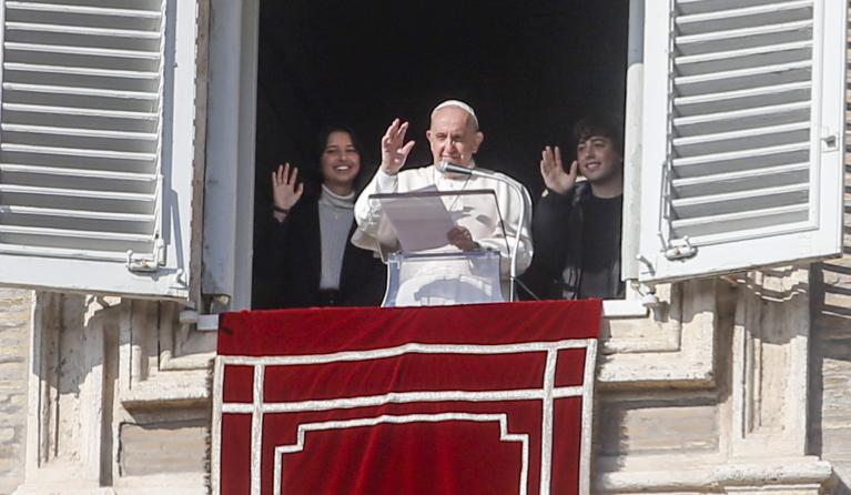  Pope Francis, flanked by two young people, waves from the window of his office overlooking Saint Peter's Square as he leads the recitation of the Angelus prayer, in Vatican City, 21 November 2021.