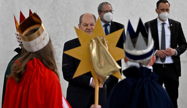 German Chancellor Olaf Scholz (C) listens to Epiphany singers (Sternsinger), groups of children who traditionally go from door to door dressed as the Three Biblical Magi offering carol blessings, as they sing outside of the Chancellery in Berlin, on January 5, 2022.