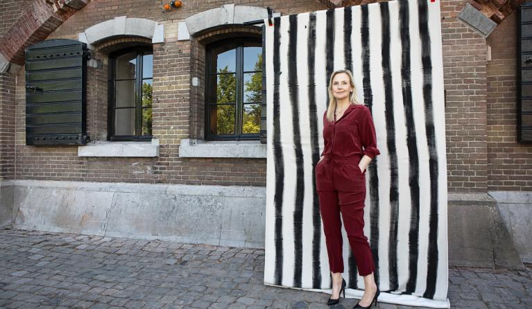 Blonde vrouw in rood pak staat voor zwart-wit-achtergrond