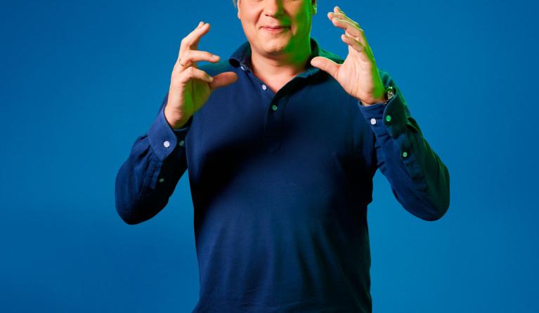 Leon Mazairac poseert voor een blauwe achtergrond in een blauwe trui