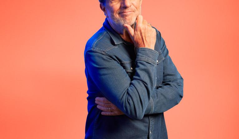 Alain Caron voor een zalmroze achtergrond