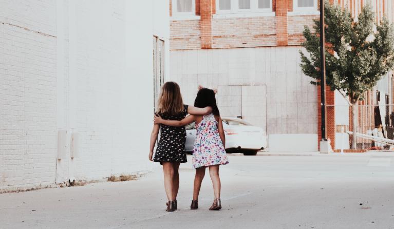 Twee meisjes lopen arm in arm op straat