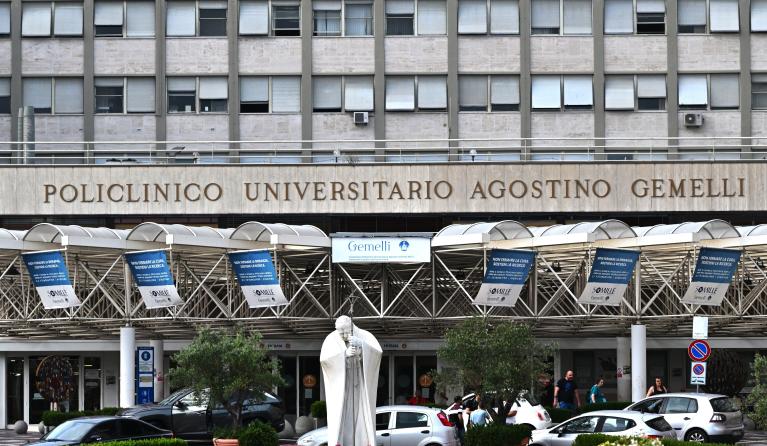 This photograph taken on June 9, 2023, shows candles and flowers layed under the statue of late Pope John Paul II at the entrance of the Rome's Gemelli hospital. Pope Francis was in a hospital in Rome for a medical check-up on June 6, according to Italian media, just over two months after he was hospitalised with bronchitis. Andreas SOLARO / AFP