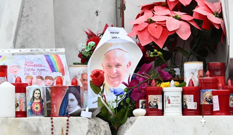 epa11920604 Candles and messages are placed at the feet of the statue of late Pope John Paul II outside of Agostino Gemelli Hospital where Pope Francis is hospitalized in Rome