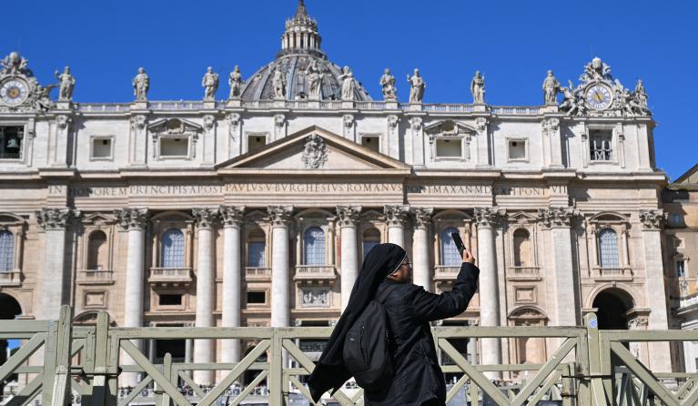 A nun takes photographs in front of the St. Peter's Basilica while the Pope is unavailable due to illness and will not lead the Angelus prayer at the Vatican on March 30, 2025. Andreas SOLARO / AFP