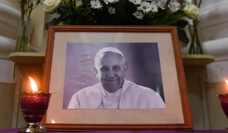 Candles light in front of a portrait of Pope Francis at the Catholic Church of St. Catherine in Saint Petersburg on April 21, 2025. 