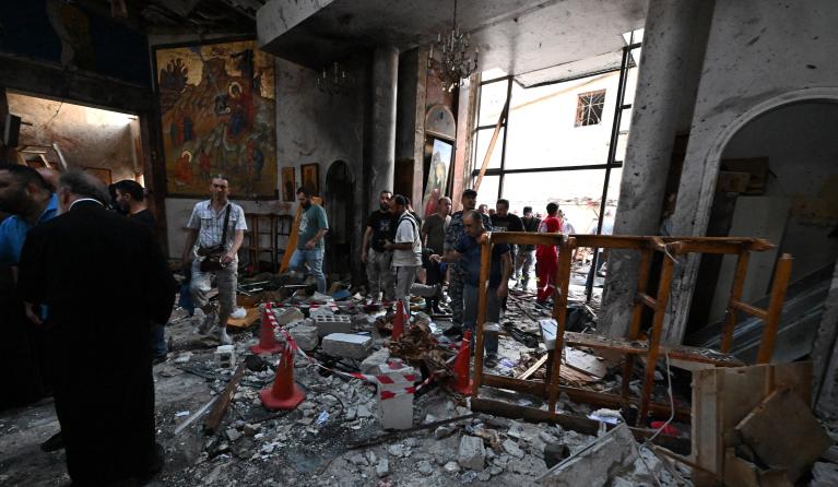 People and rescuers inspect the damage at the site of a reported suicide attack at the Saint Elias church in Damascus' Dwelaa area on June 22, 2025. Syrian state media reported a suicide attack on a Damascus church on June 22 that caused casualties, as AFP correspondents at the scene saw first responders transporting people from the site. LOUAI BESHARA / AFP