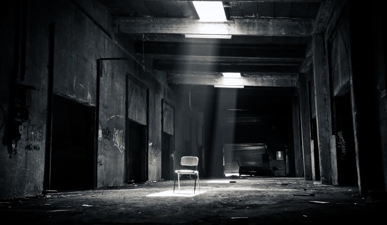 een donkere steeg zwart wit met een verlichte stoel