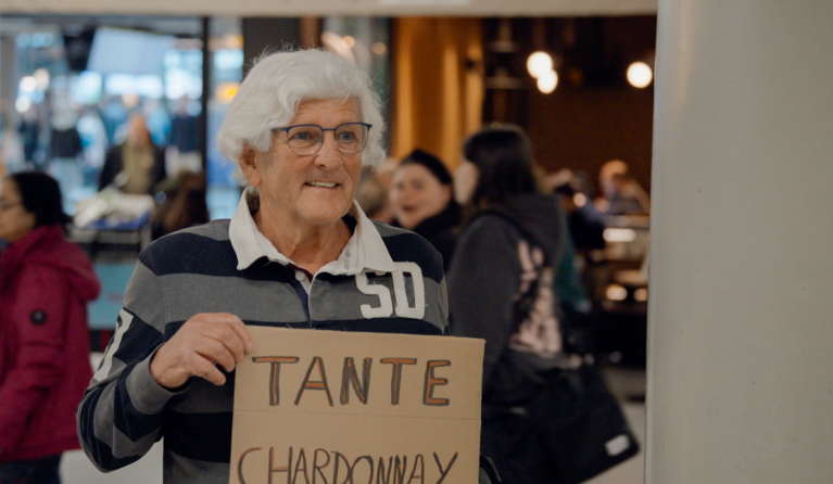 Een man wacht met een bordje op Schiphol