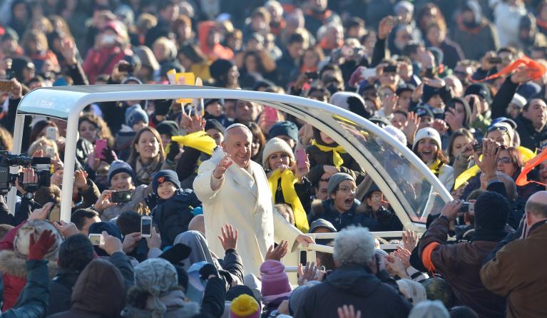Pope Francis (C) greets the crowd as he arrives for his general audience at St Peter's square on December 18, 2013 at the Vatican. AFP PHOTO / ALBERTO PIZZOLI