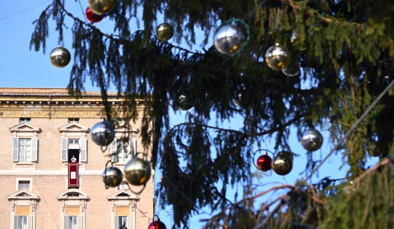 Pope Leo XIV is seen through the Christmas tree as he addresses the crowd from a window of the apostolic palace overlooking St. Peter's Square during the Angelus prayer in The Vatican on December 21, 2025.  Andreas SOLARO / AFP