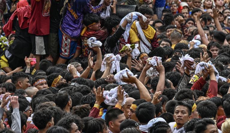 A Catholic devotee sprinkles water during the annual religious procession of Jesus the Nazarene in Manila on January 9, 2026. Tens of thousands of Philippine Catholics twirled white cloths and chanted "Viva, viva" as a historic statue of Jesus Christ was paraded through the streets of Manila on January 9 in the nation's biggest annual religious event. Jam STA ROSA / AFP