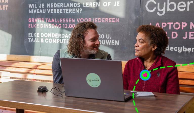 Twee mensen achter een laptop kijken elkaar aan