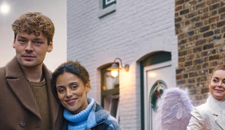 twee personen en een engel voor een rode auto