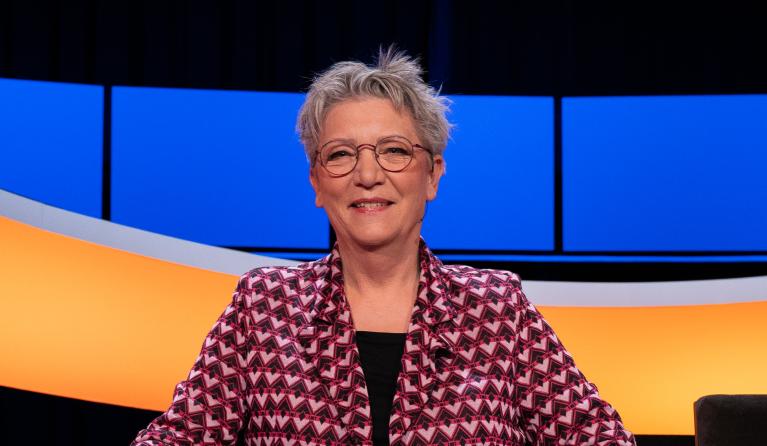 Vrouw met kort grijs haar en roze vest in studio