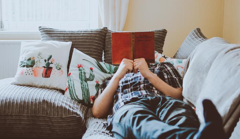 Iemand ligt lekker te chillen op de bank met een boek