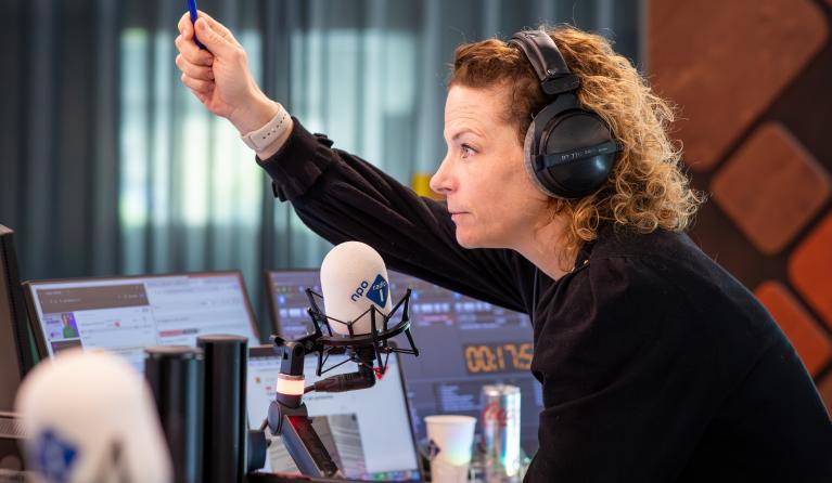 Vrouw in radiostudio met haar hand omhoog