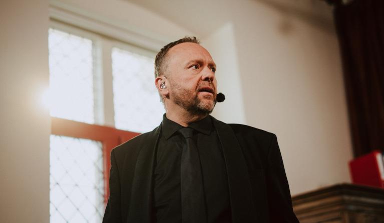 Man met microfoon en zwart pak