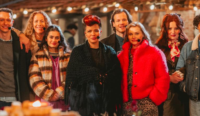 Groep mensen staat voor een gezellig verlicht huis