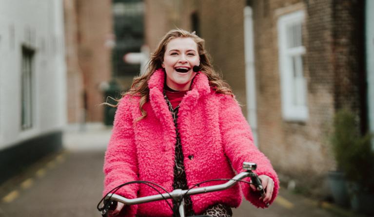 Vrolijke vrouw zingend op een fiets