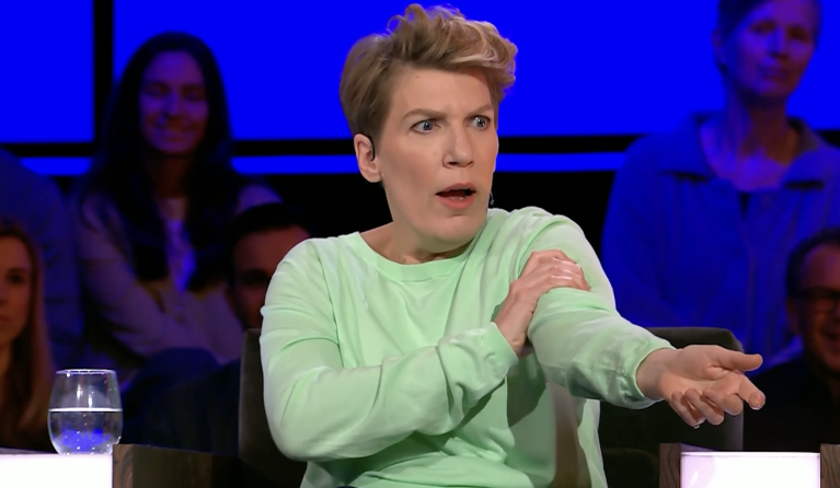 Vrouw met groene trui houdt haar arm vast