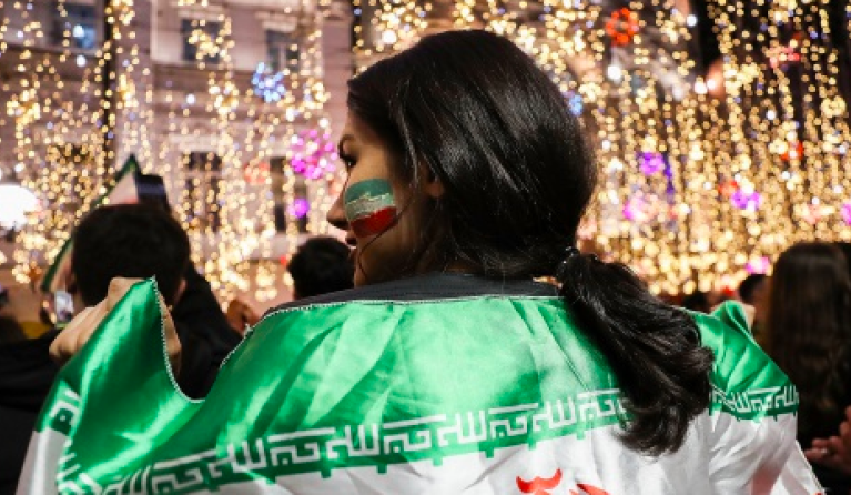 Iraanse supporter met vlag om haar schouders 