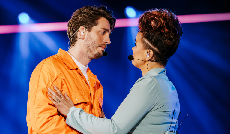 Man en vrouw kijken elkaar intens aan op een podium